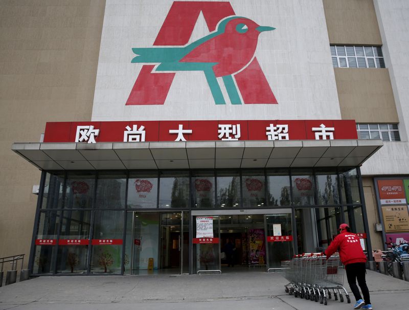 FILE PHOTO: An employee carries shopping carts into Sun Art Retail Group's Auchan hypermarket store in Beijing,